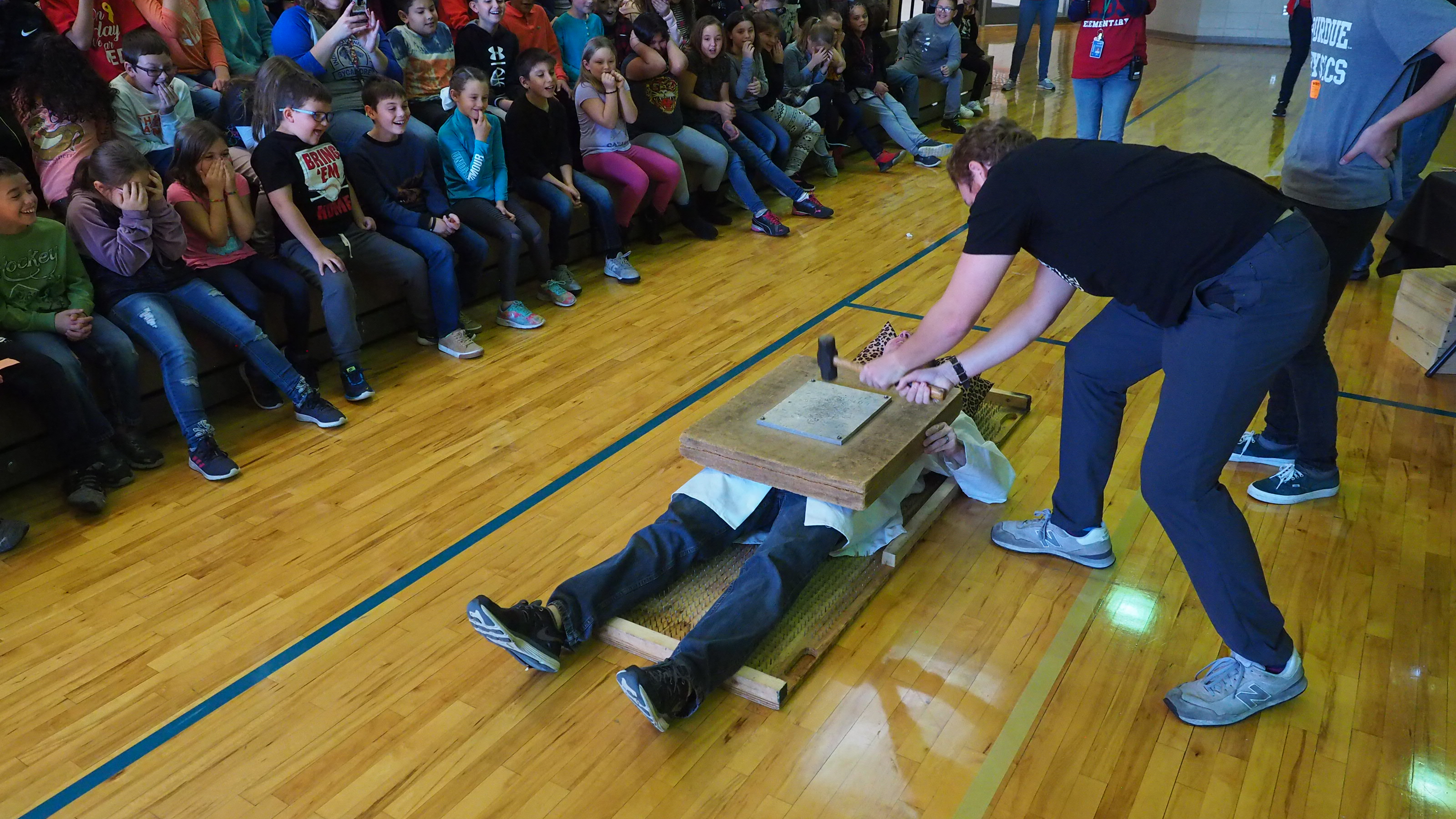 A hammer on concrete with someone on a bed of nails.